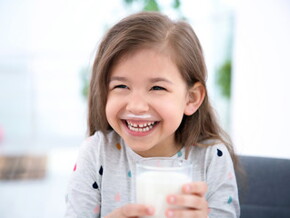 Niña sonriente tomando un vaso con leche