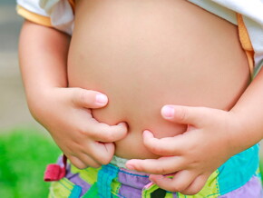 Niño tocando su estómago con la camisa levantada