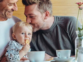 Niña comiendo galletas para bebés con su papá y abuelo.