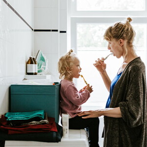 Mamá y niña en el baño cepillándose en el baño.