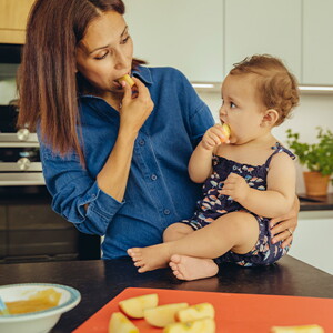 Mamá y bebé comiendo fruta en la cocina