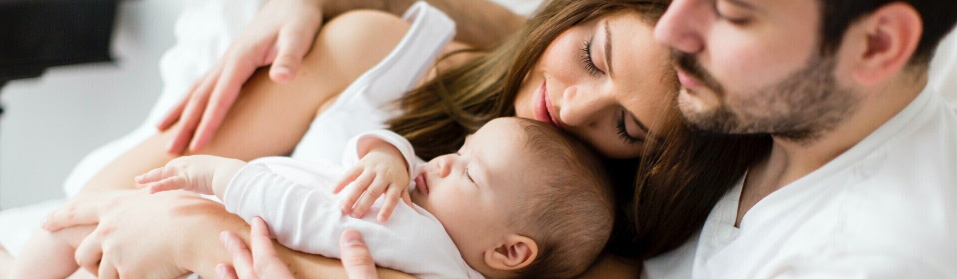 Mamá y papá acostados con su bebé